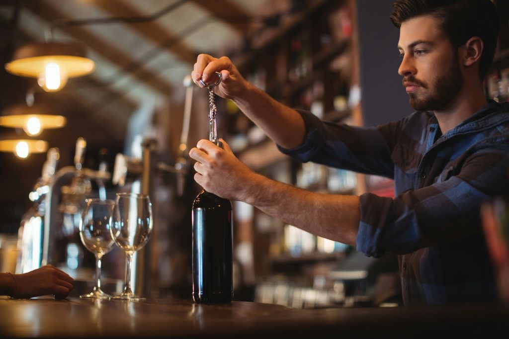 Image of a man opening a bottle of wine.